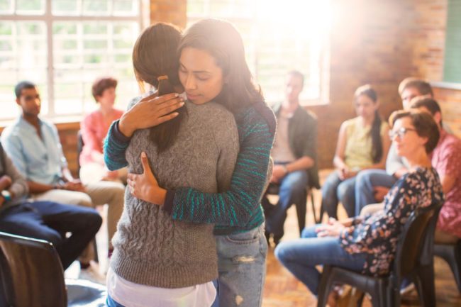 a woman hugs another woman and thanks her for vulnerability during a group therapy session