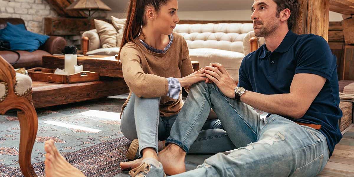 a man and woman sit close to each other on the floor discussing marijuana addiction treatment
