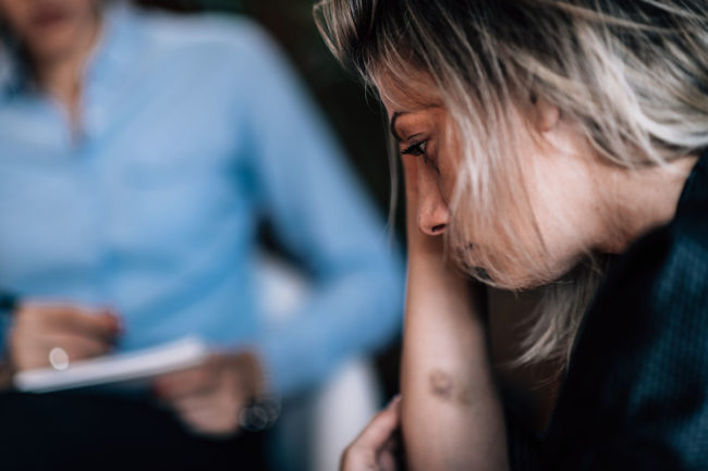 Signs of a Heroin Overdose woman distraught in treatment dealing with life after a heroin overdose