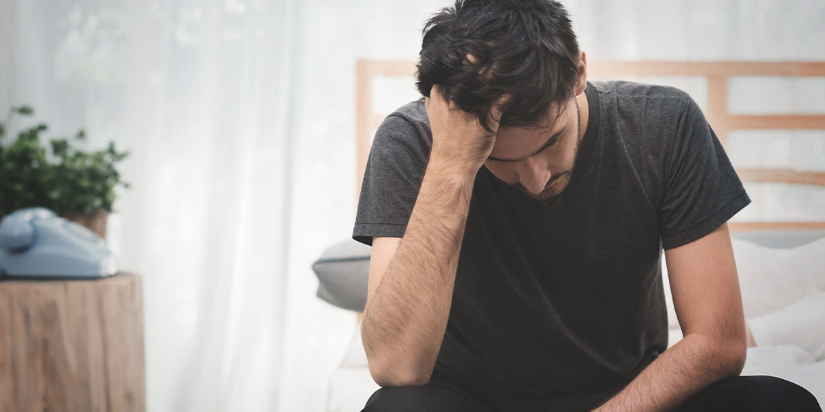 What are the Long-Term Effects of Heroin Use man sitting with hand on head struggling with long-term effects of heroin use