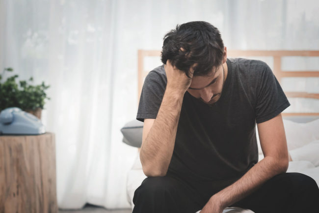 What are the Long-Term Effects of Heroin Use man sitting with hand on head struggling with long-term effects of heroin use