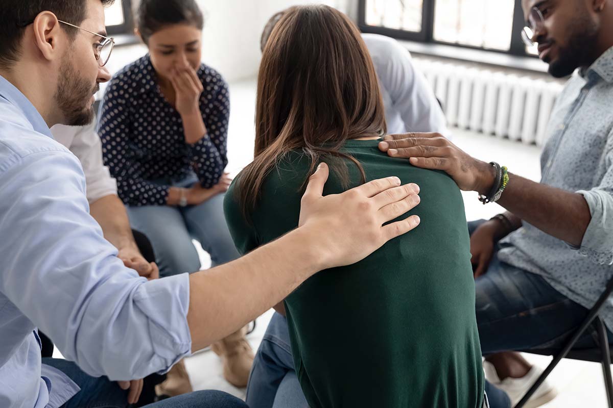 group therapy members consoling woman in residential detox center