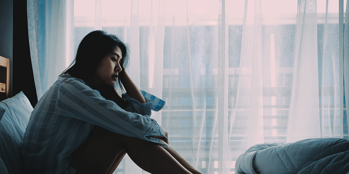 a woman sits by her window feeling defeated as she thinks about commonly abused prescription drugs