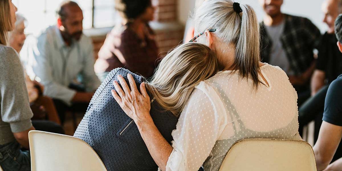 a woman consoles a fellow group member in group there at an outpatient alcohol rehab