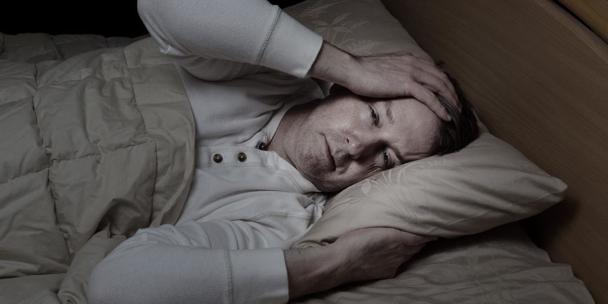 What Are The Side Effects of Meth a person lies in bed struggling to sleep and showing side effects of meth