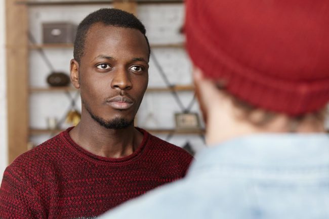How to Help Someone With Meth Addiction a man looks and listens to a man standing in front of him who is talking about how to help someone with meth addiction