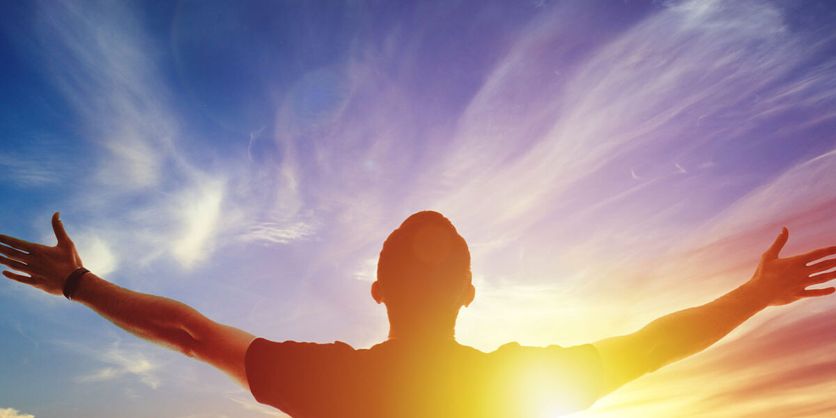 a man is open armed toward the sunrise sky and feeling enlightened by learning how to overcome meth addiction