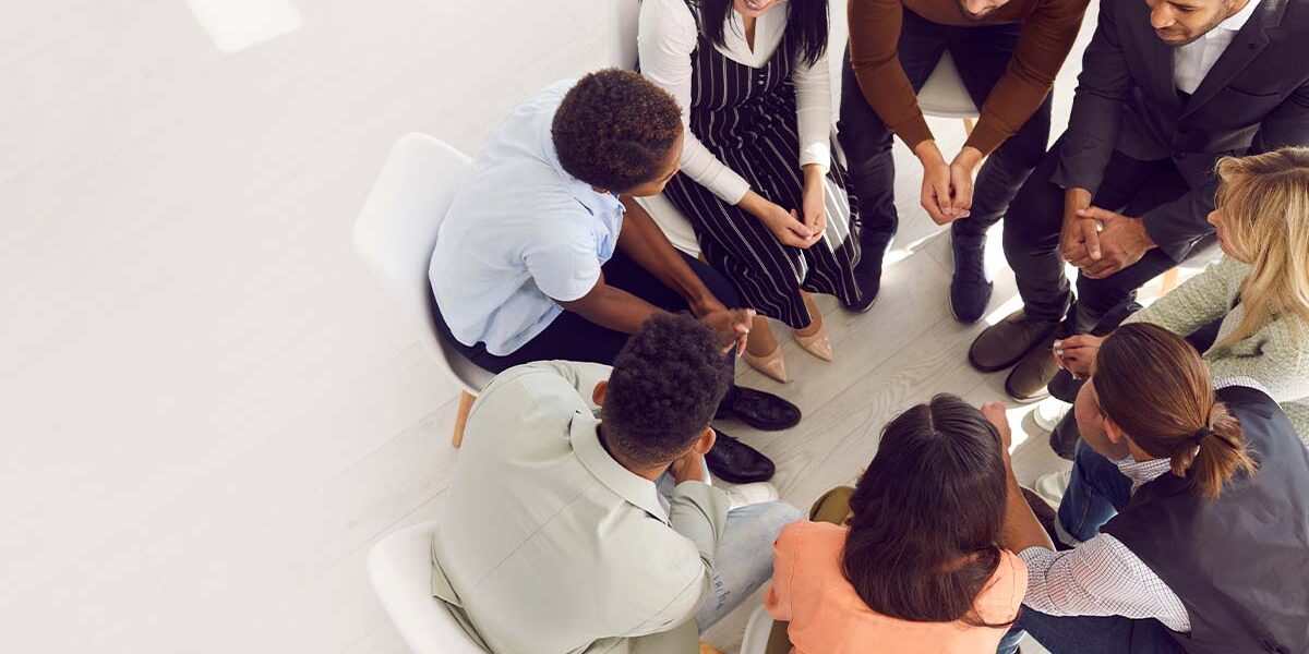 a group of people sit in a circle discussing the benefits of IOP for their recovery