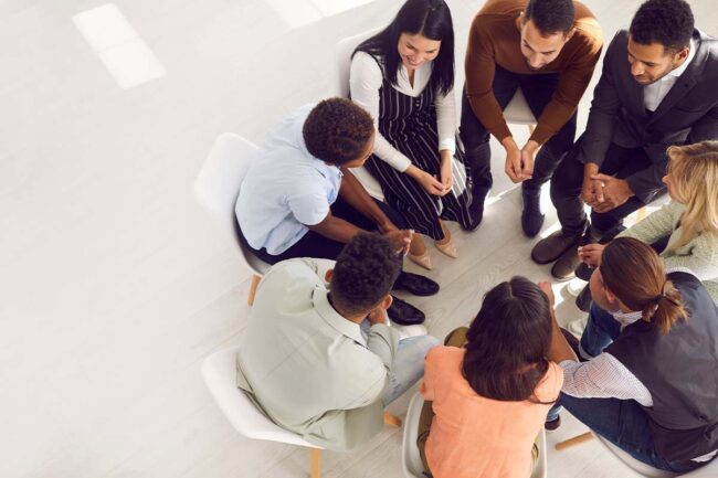 a group of people sit in a circle discussing the benefits of IOP for their recovery