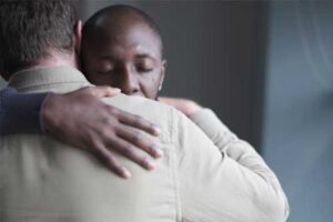 a man hugs another group member in the man's aftercare program