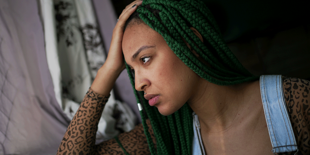 What-Are-Long-Term-Effects-of-Synthetic-Drugs a distraught woman holds her hand to her head and looks away thinking about the long-term effects of synthetic drugs