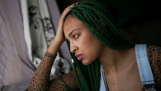 What-Are-Long-Term-Effects-of-Synthetic-Drugs a distraught woman holds her hand to her head and looks away thinking about the long-term effects of synthetic drugs