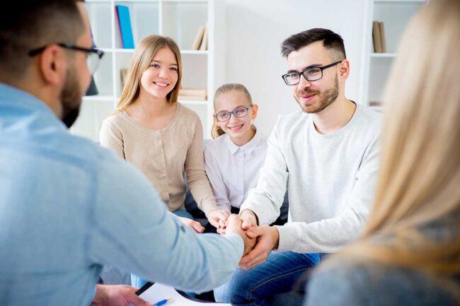 3-Goals-Of-Family-Therapy-For-Communication a family sits together in a circle reaching out to each others hands and discussing their goals for family therapy