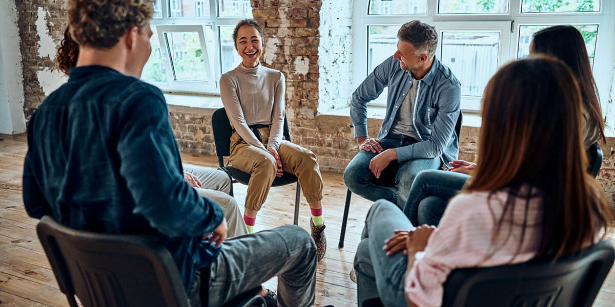 Picture of support group during meeting with professional therapist. a group of people sit together in a circle in therapy and discuss the stages of alcohol recovery