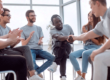 a group of people sit in a circle together two people shake hands while discussing how choosing a drug rehab in spokane wa helped their recovery