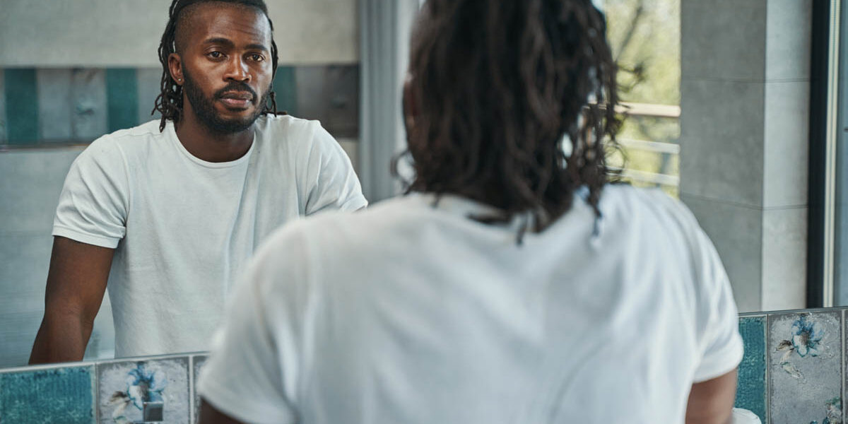 man looks at his reflection in a bathroom mirror wondering to himself is vicodin addictive