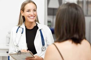 an addiction specialist holds a clipboard and takes notes as she listens to the patient asks questions about php drug treatment