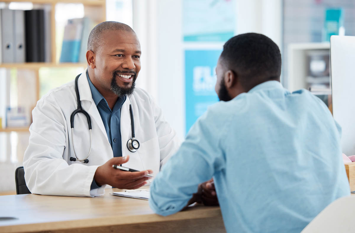 What Is the Goal of a Partial Hospitalization Program a medical professional sits across from a patient at a table and discusses the benefits of a php drug rehab