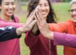 women in recovery stand together in a circle and high five in the middle of the circle