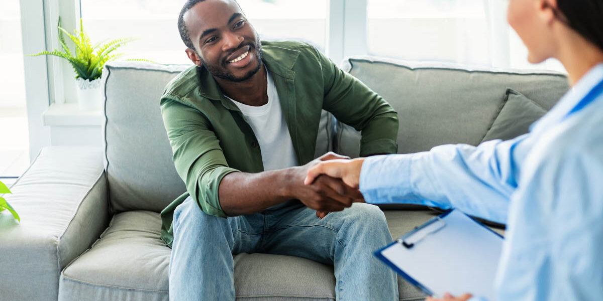 male patient sits on a couch and hand shakes a therapist after learning about iop and its meaning