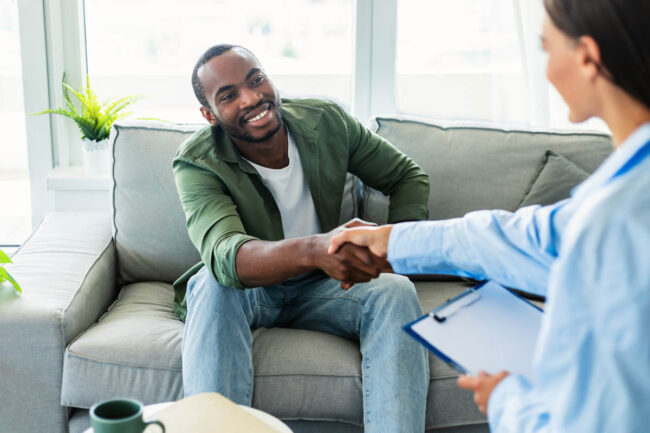 male patient sits on a couch and hand shakes a therapist after learning about iop and its meaning
