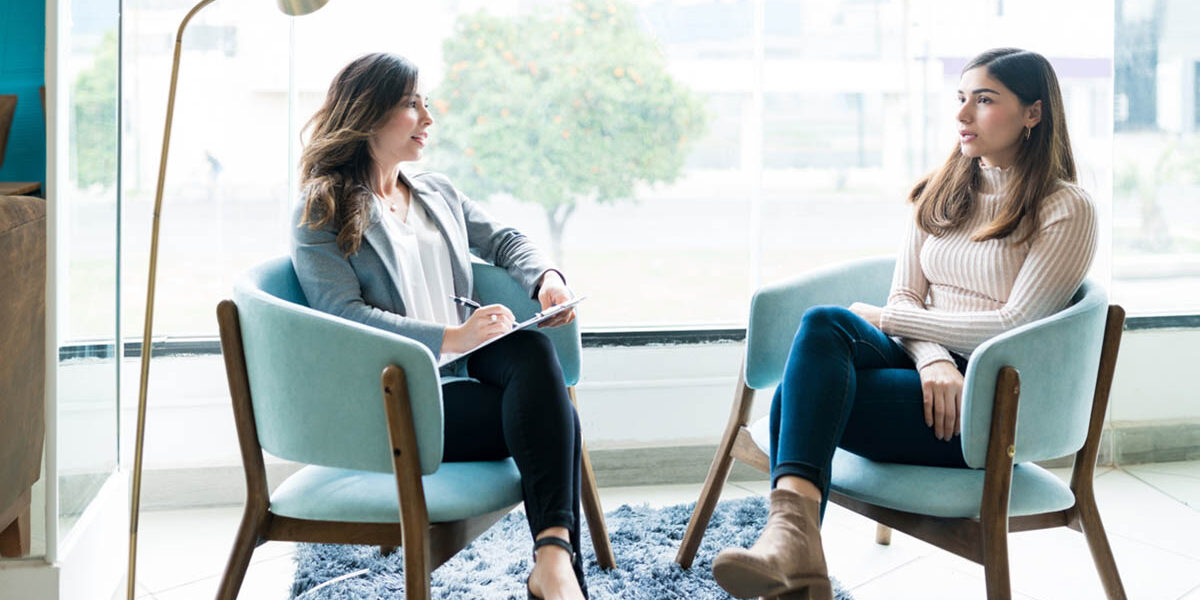 CBT vs DBT Choosing the Best for Your Condition a therapist sits in a chair across from a patient explaining of cbt vs dbt