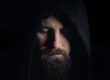 man with a beard wearing a black hoodie in the dark wonders about the differences of crack vs cocaine
