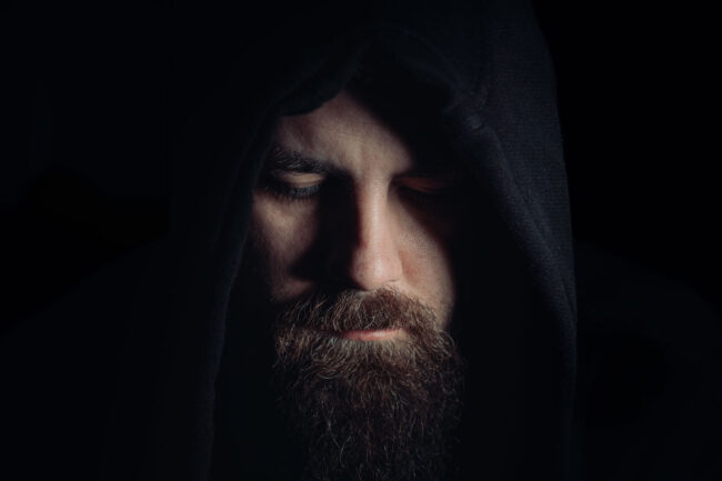 Crack vs. Cocaine – What Are the Similarities and Differences man with a beard wearing a black hoodie in the dark wonders about the differences of crack vs cocaine