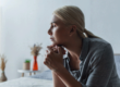 woman with blonde hair sits on a bed looking off into the distance asking herself can alcohol cause anemia
