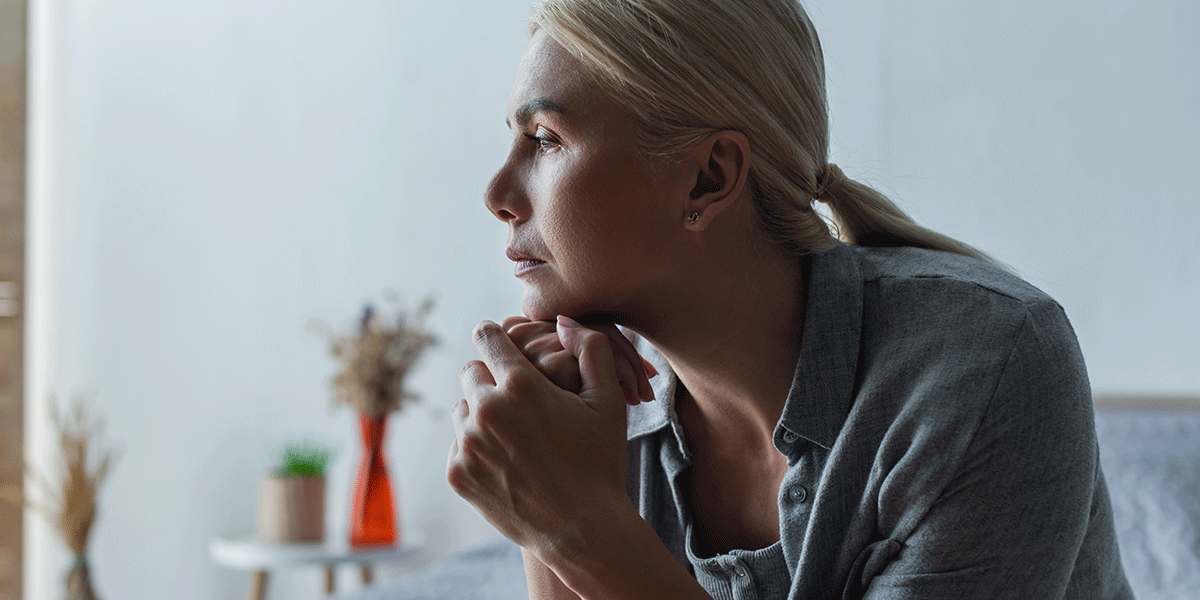 Does-Alcohol-Cause-Anemia-and-Can-It-Be-Reversed woman with blonde hair sits on a bed looking off into the distance asking herself can alcohol cause anemia