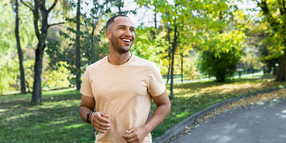 Effective Coping Strategies for Addiction Cravings smiling man is outside in a park thinking about how his coping strategies have benefited him