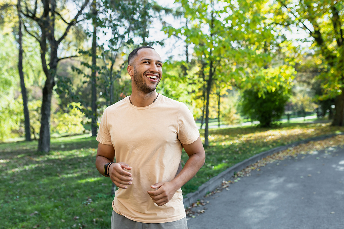 Effective Coping Strategies for Addiction Cravings smiling man is outside in a park thinking about how his coping strategies have benefited him