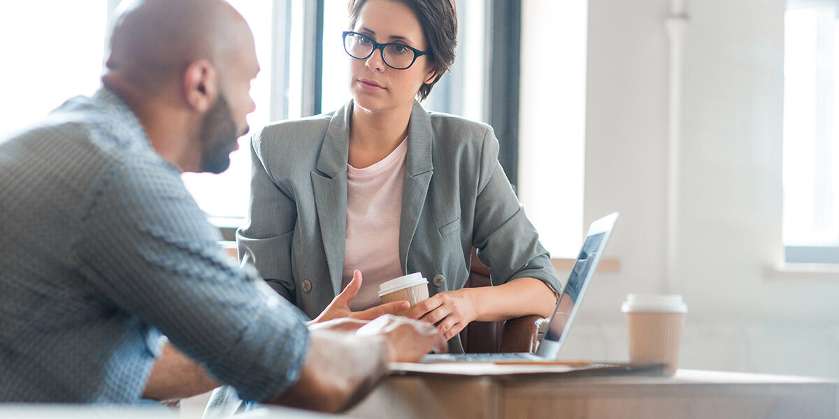 The Science Behind Addiction Explained a woman with glasses sits at a table with a laptop while talking to a man about addiction science