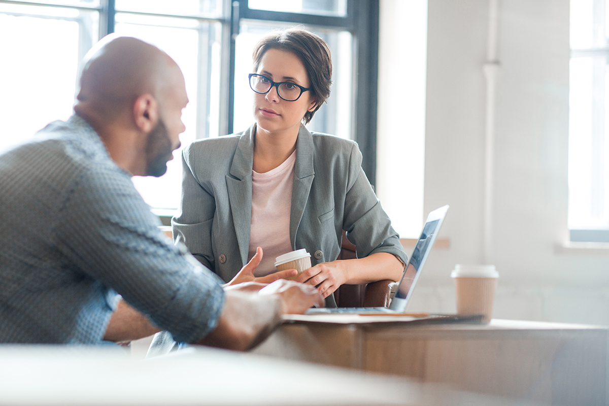 The Science Behind Addiction Explained a woman with glasses sits at a table with a laptop while talking to a man about addiction science