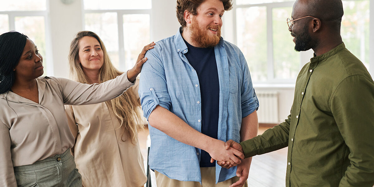 Overcoming Cocaine Addiction- A Step-by-Step Guide to Recovery three people congratulate and shake hands with a man for overcoming cocaine addiction