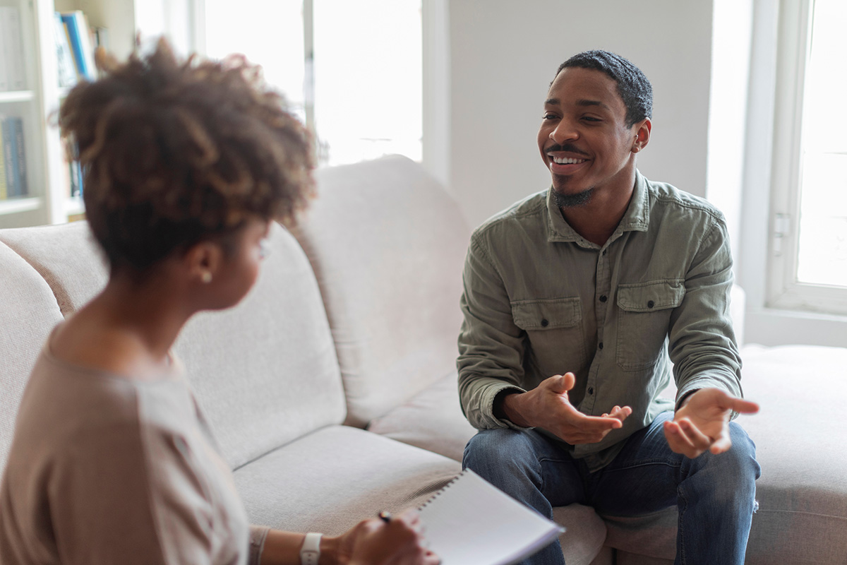 a man and woman sit on a couch and talk about medical supervision in alcohol detox