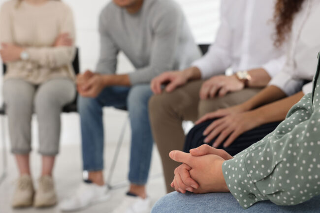 a group of people sit in a circle in group therapy in their medical detox program