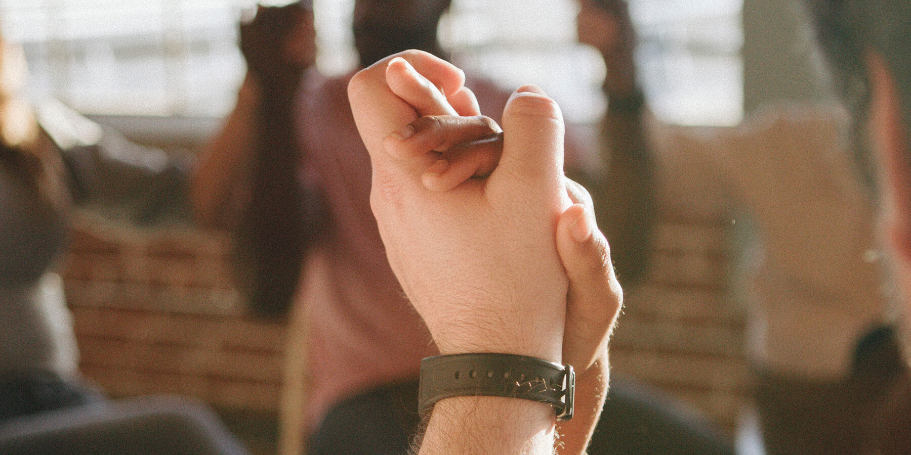 group in alcohol detox sit together and hold each others hands in support of recovery