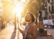 smiling woman with glasses holds her phone while outside enjoying her life after rehab