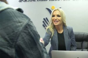 woman at front desk smiling and shaking hands with person