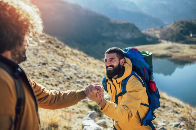 Effective Strategies for Preventing Relapse two people hold hands and are hiking on a mountain as one of their effective strategies for preventing relapse
