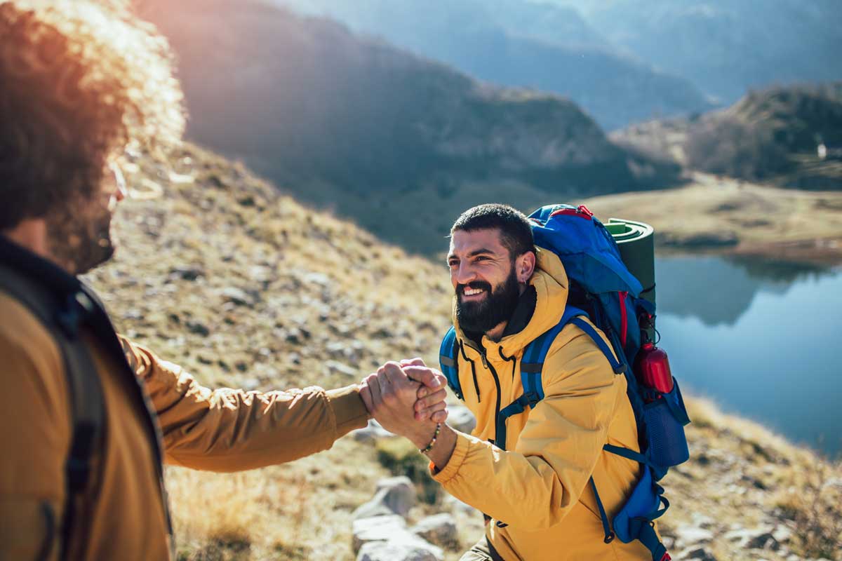Effective Strategies for Preventing Relapse two people hold hands and are hiking on a mountain as one of their effective strategies for preventing relapse