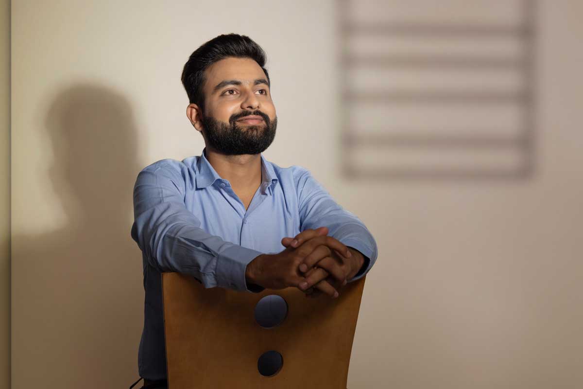 How Long Does Medical Detox Take smiling man stands near a chair and thinks about how long does medical detox take