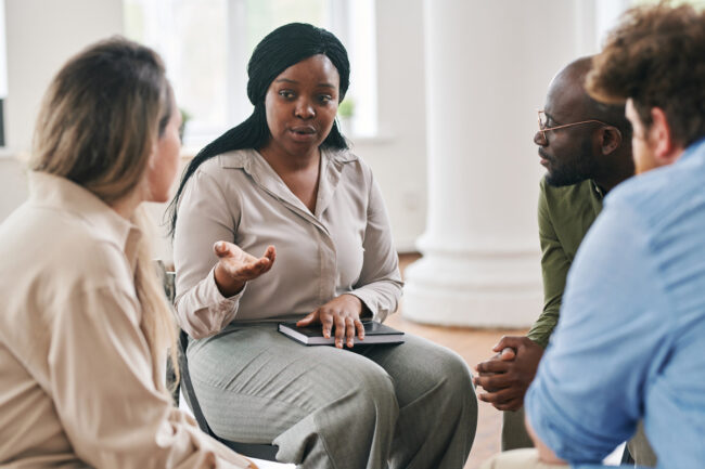 Woman speaking to others in group therapy session