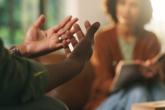 Man explaining to counselor writing in book