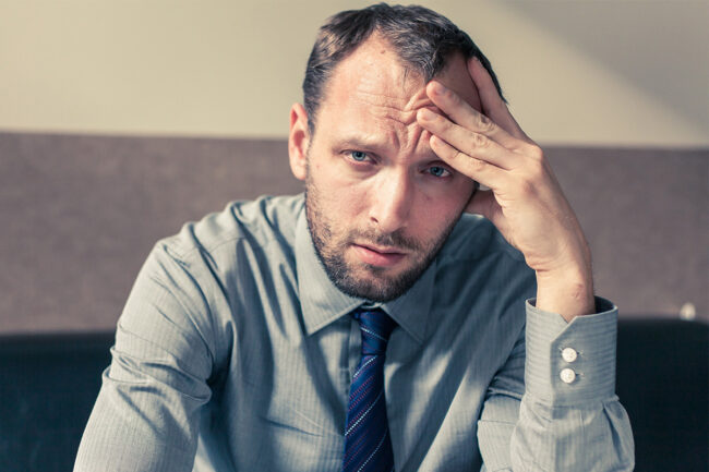Signs of Alcohol Addiction How to Know When Drinking Has Become a Problem Man in business casual hungover at work