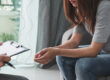 Professional psychologist doctor holding clipboard and filling medical patient information consulting his depressed patient